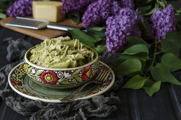 Penne pasta with pesto sauce and a bouquet of lilac