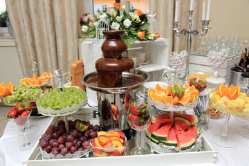 Owoce, desery i płynna czekolada, słodkie ciasta na stole urodzinowym w restauracji. - obrazy, fototapety, plakaty