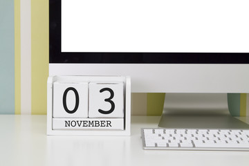 Cube shape calendar for NOVEMBER 3 and computer keyboard on table. 