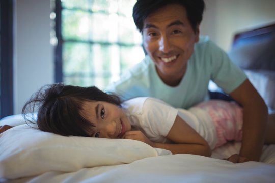 Father and daughter having fun on bed in bed room