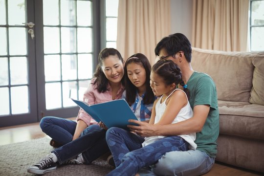 Family watching photo album together in living room