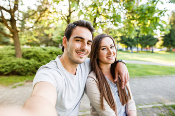 Fototapeta premium Cute and happy couple enjoying in park and taking selfie