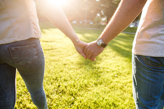 Young couple in love walking on sunny day  and holding their hands