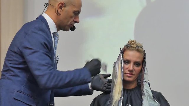 Stylist man cuts hair blonde Italian in a hairdressing salon