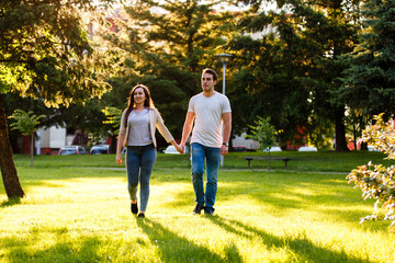 Lovely couple at park walking together on sunny day holding their hands