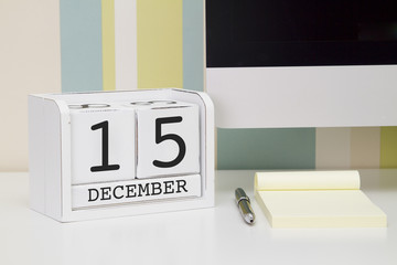 Cube shape calendar for DECEMBER 15 and computer keyboard on table. 