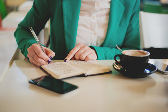 Young business woman writing notes in journal