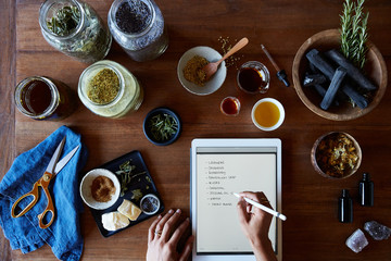 Small Business owner working on digital tablet while making skincare products