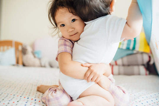 Toddler girl hugging her little brother