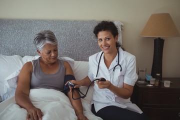 Female doctor measuring blood pressure of a senior woman