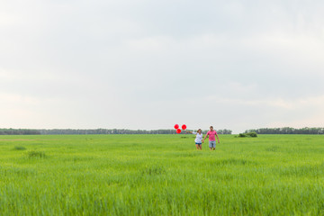 beautiful young couple hugging and kissing in a field with colored balloons