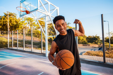 Man is holding a basket ball and laughing,street ball,sport competitions,afro,outdoor portrait,sport games,handsome black man,pretty,man holding ball,sportsman,black sport shorts,sports shoes