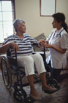 Female doctor interacting with senior woman on wheelchair