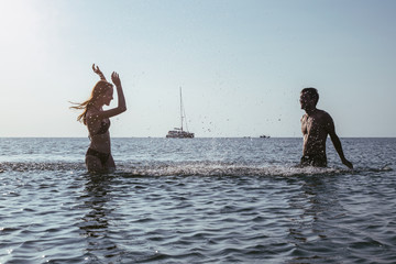 Fun in the sun - couple splashing water on each other