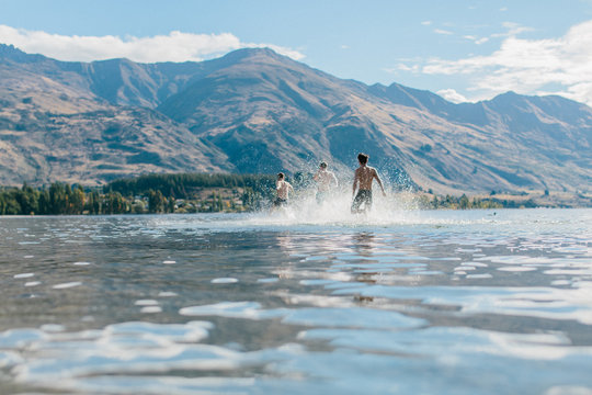 Three friends splash around in the warm waters of a lake on a late summer day 