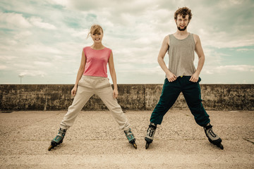 Two people exercise stretch outdoor on rollerblades.