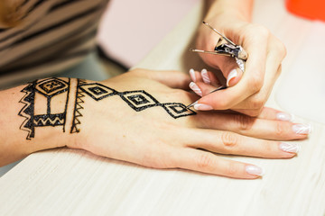 young woman mehendi artist painting henna on the hand
