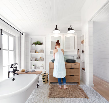 Woman washing hands in bathroom in rustic modern farmhouse