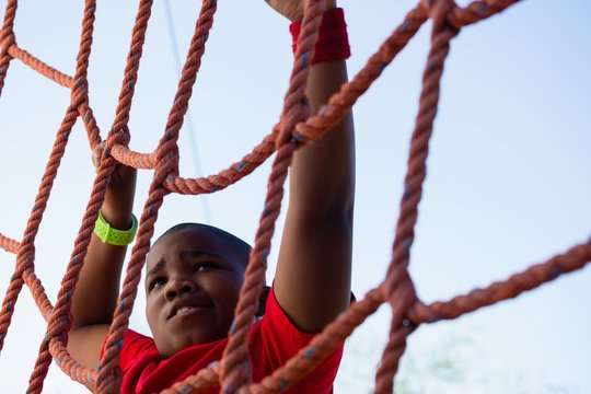 Boy climbing a net during obstacle course training - Powered by Adobe
