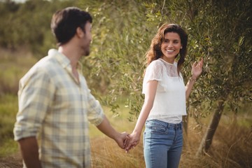 Smiling couple standing by tree at farm