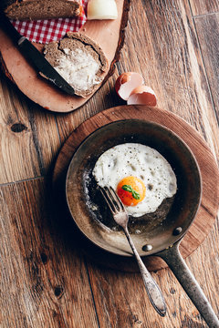 fried egg in cast iron pan, bread and butter on wooden background