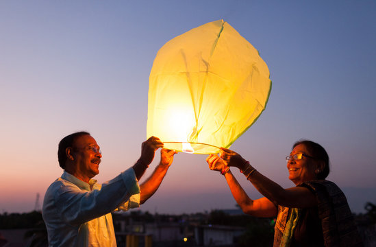 Senior couple releasing sky lantern to the sky at twilight