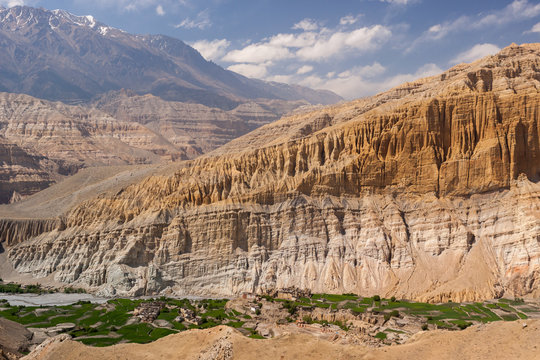 Village in Upper Mustang, Nepal, with unique rock formations and Himalayas in the background.