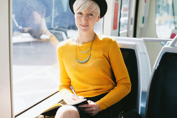 Portrait of a modern and chic woman sitting in the train of the city