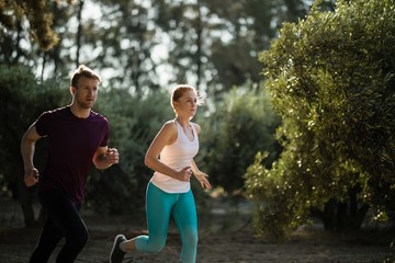 Determined young couple running on field at farm