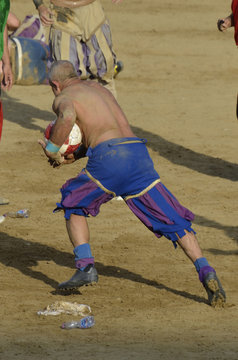 Calciante in azione che corre con la palla durante la partita di calcio storico fiorentino
