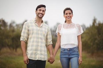 Smiling young couple holding hands at olive farm