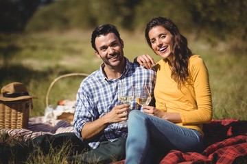 Couple holding wineglasses while sitting on blanket
