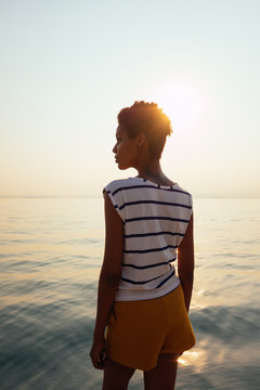 Woman looking the sea at sunset