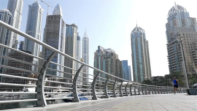 Low angle view of athletic fitness man running jogging in Dubai Marina in the morning, slow motion