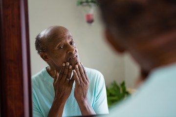 Concerned senior man looking at mirror