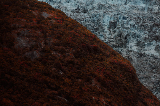 The split terrain between a rocky and icy glacier and the red umber colored grass