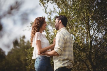 Fototapeta premium Loving young couple standing by trees at farm