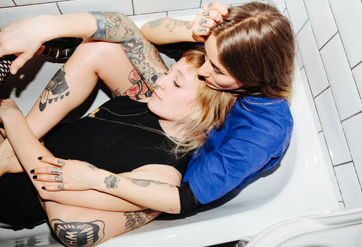Two beautiful tattooed women cuddling in a bath