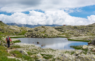 Female trekker walking along mountain lake.