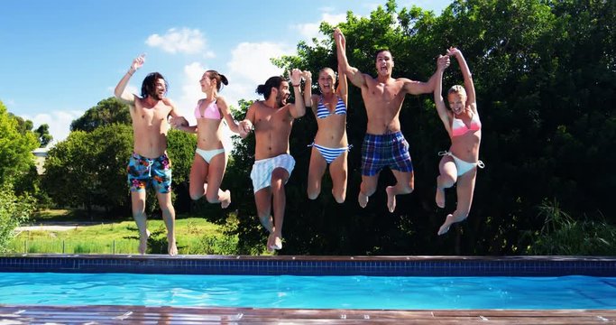 Happy friends jumping into swimming pool