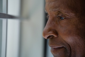 Close up of thoughtful senior man looking out through window