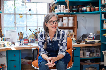 Portrait of senior woman with grey hair inside her pottery studio
