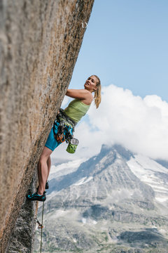 young sporty female rock climber climbing in the mountains