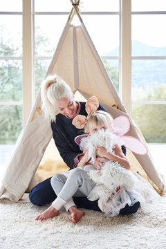 Mom and daughter playing in front of teepee in living room