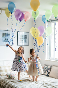 Girls playing with balloons in bedroom