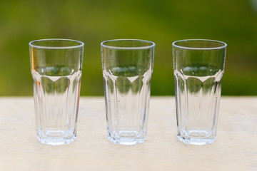 Three empty glass transparent cup on the table against the background of the chair and sofa