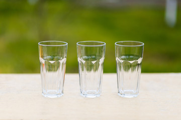 Three empty glass transparent cup on the table against the background of the chair and sofa