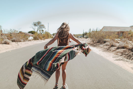 A carefree young woman stands in the middle of a desert road
