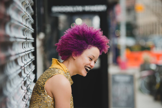 Young woman with curly purple hair laughs