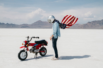 portrait of young male wearing american flag while riding motorcycle through desert salt flat